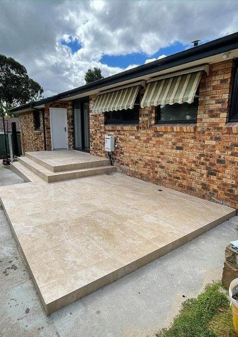 A Brick House With a Concrete Patio in Front of It — Maestro Tiling Services In Latham, ACT