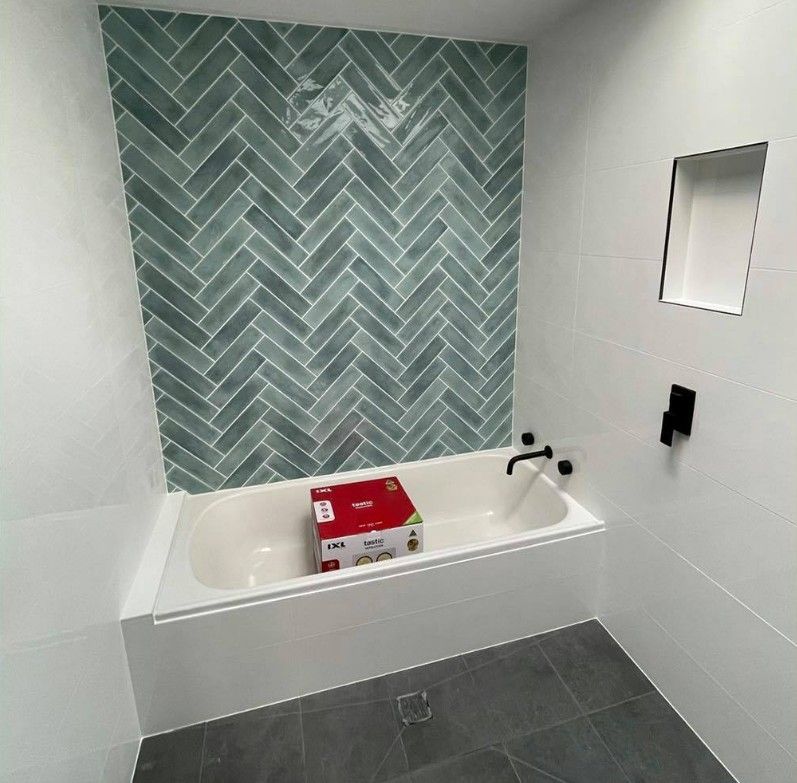 A Bathroom With a Bathtub and a Herringbone Tile Wall — Maestro Tiling Services In Latham, ACT