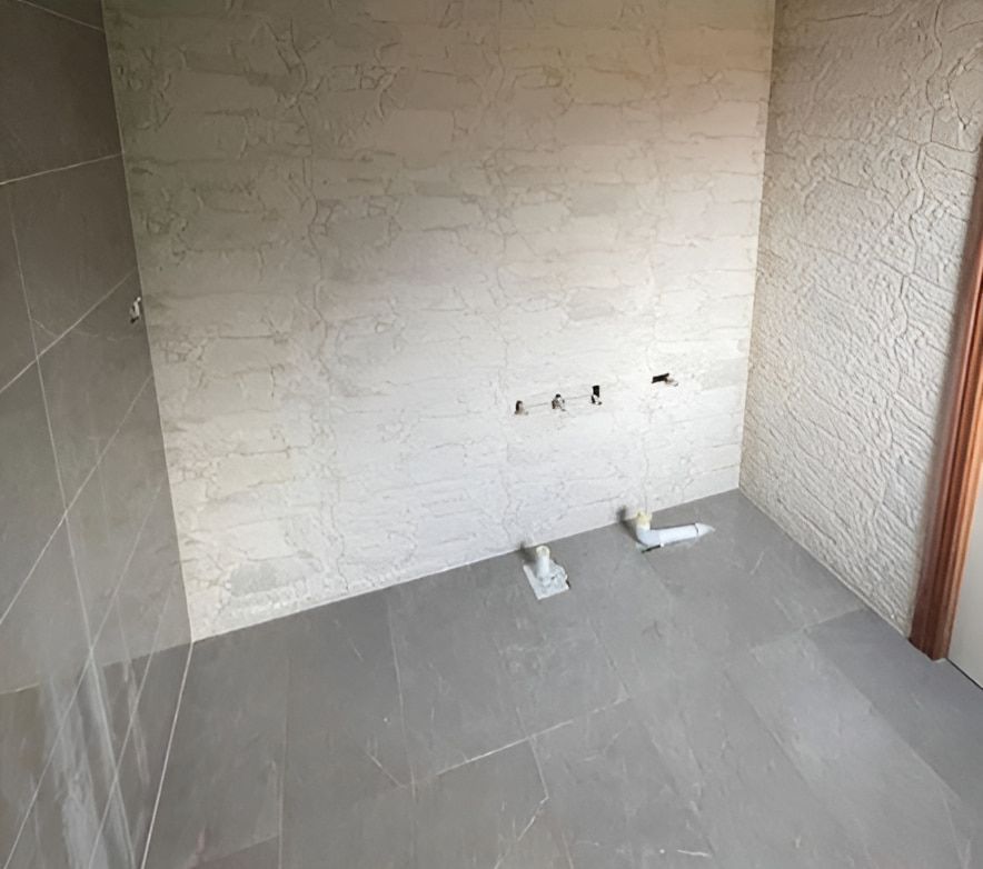 A Bathroom With a Tiled Floor and a Brick Wall — Maestro Tiling Services In Murrumbateman, NSW