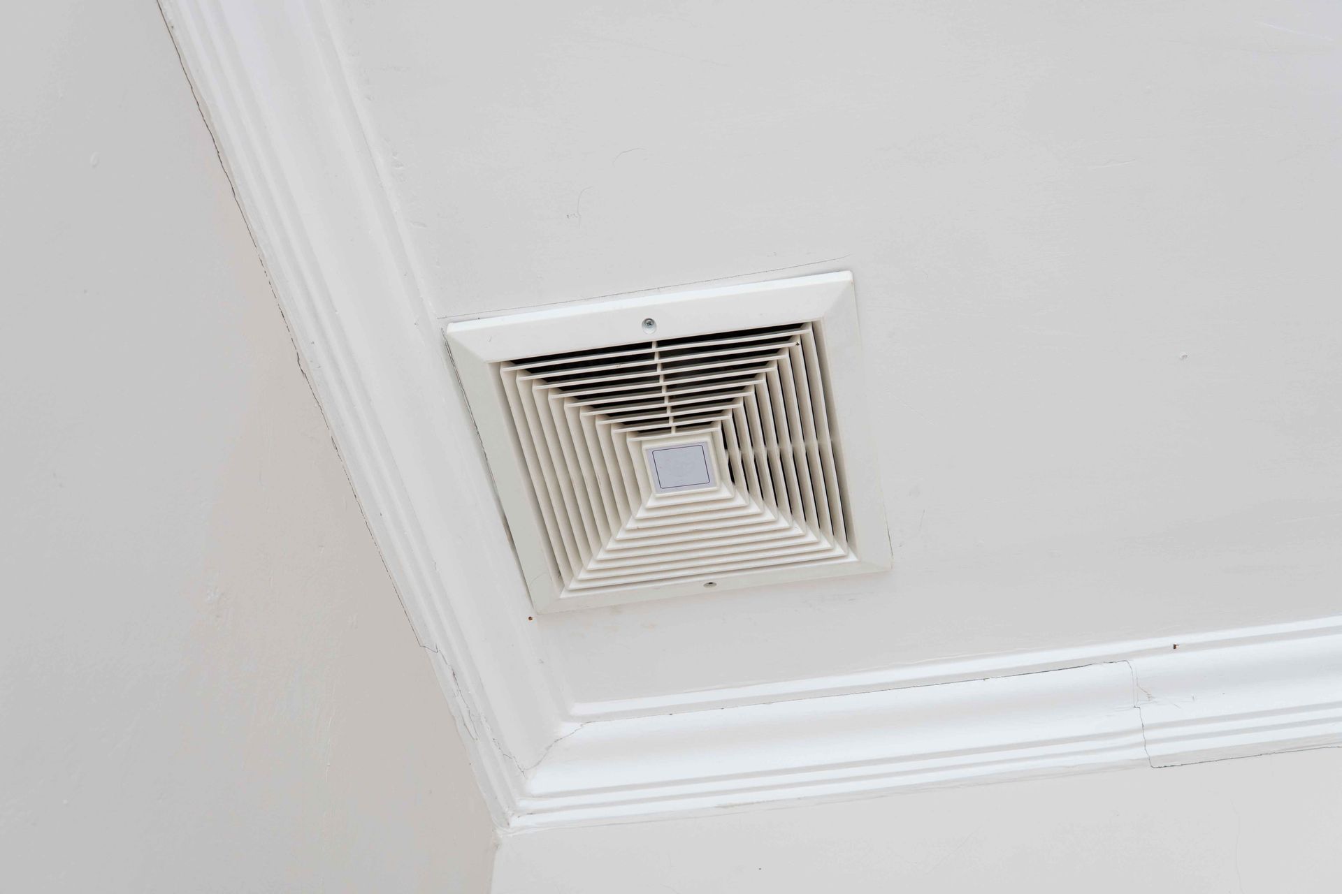 Plafond blanc avec un ventilateur d'aération carré encastré.