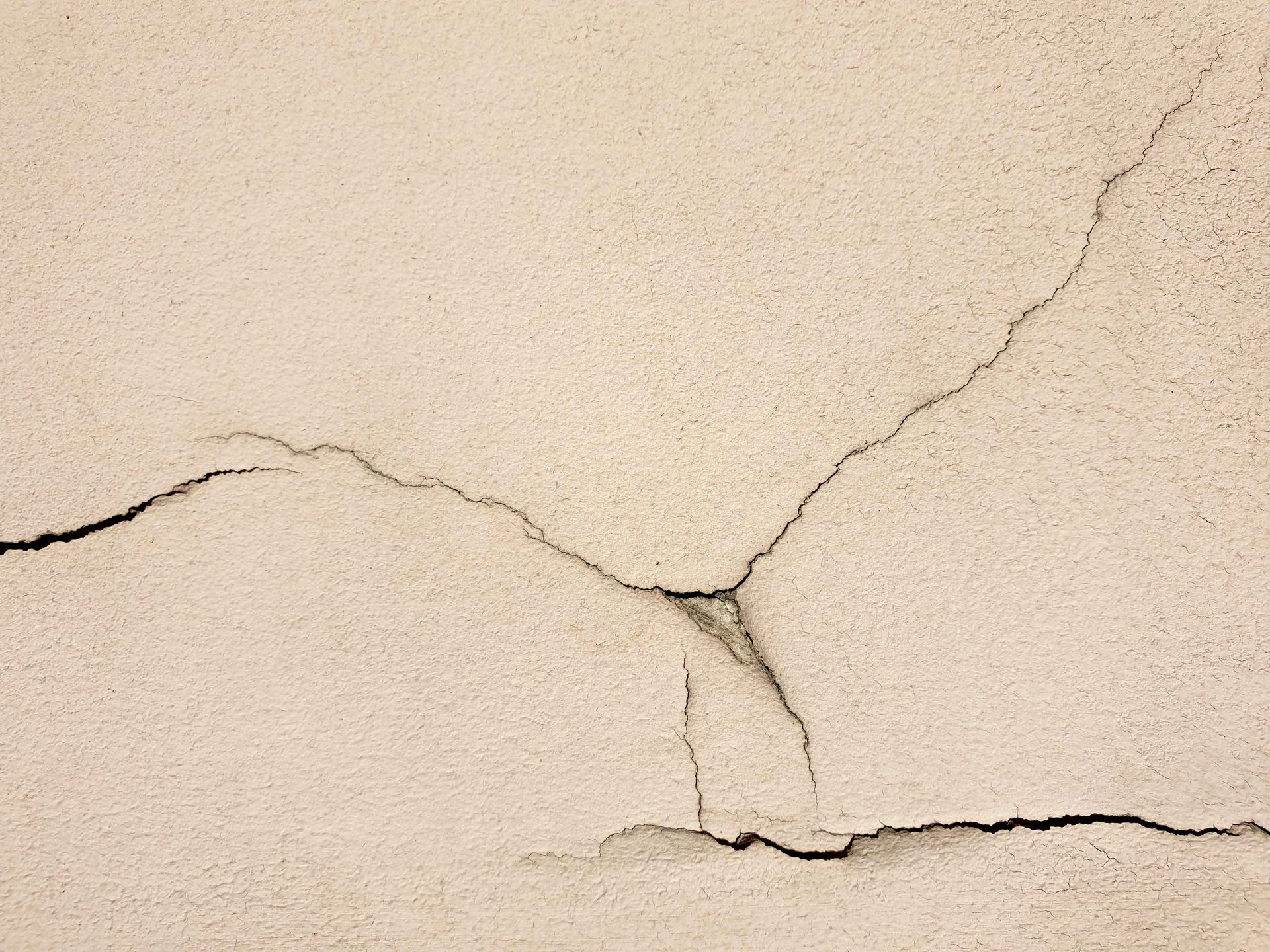 Mur beige fissuré sur toute sa surface.