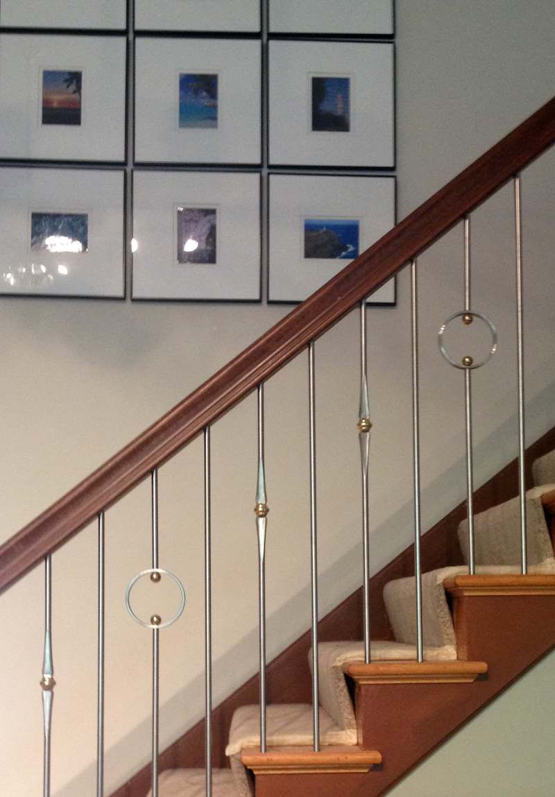 Staircase with wooden handrail, white balusters, and framed photos on the wall above.