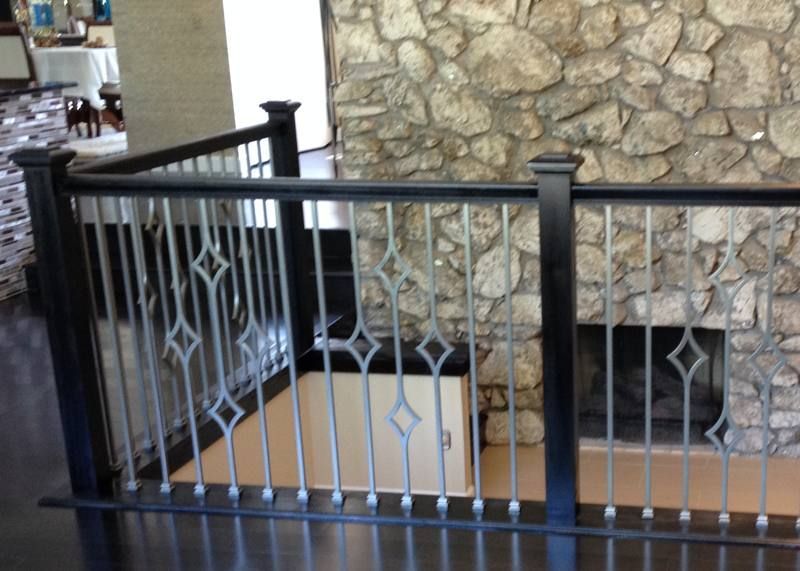 Black metal railing in front of a stone wall and outdoor walkway