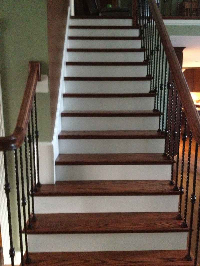 Indoor staircase with white steps, dark wood treads, and black iron railings