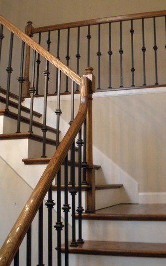 Interior staircase with wooden handrail, dark balusters, and beige walls.