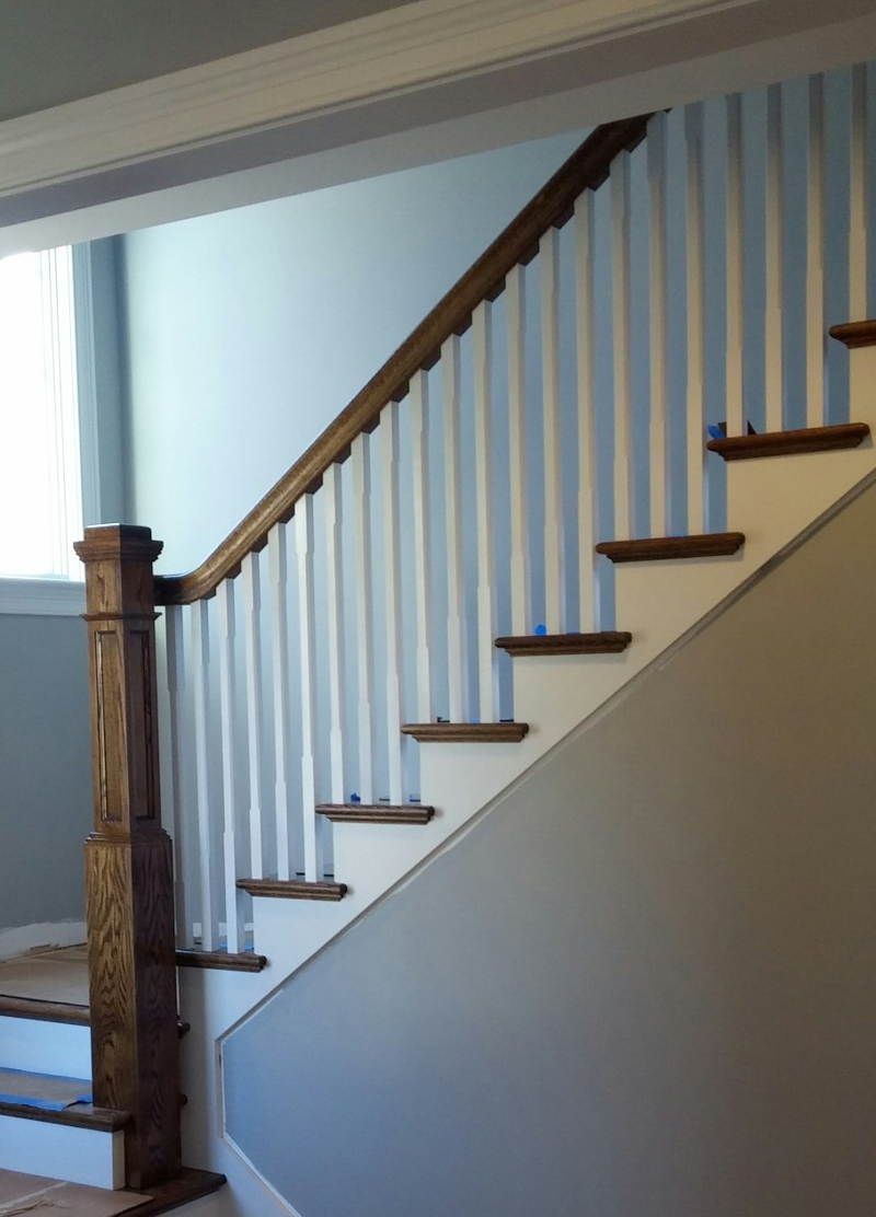 Staircase with white balusters, dark wood handrail, and beige wall in a home interior