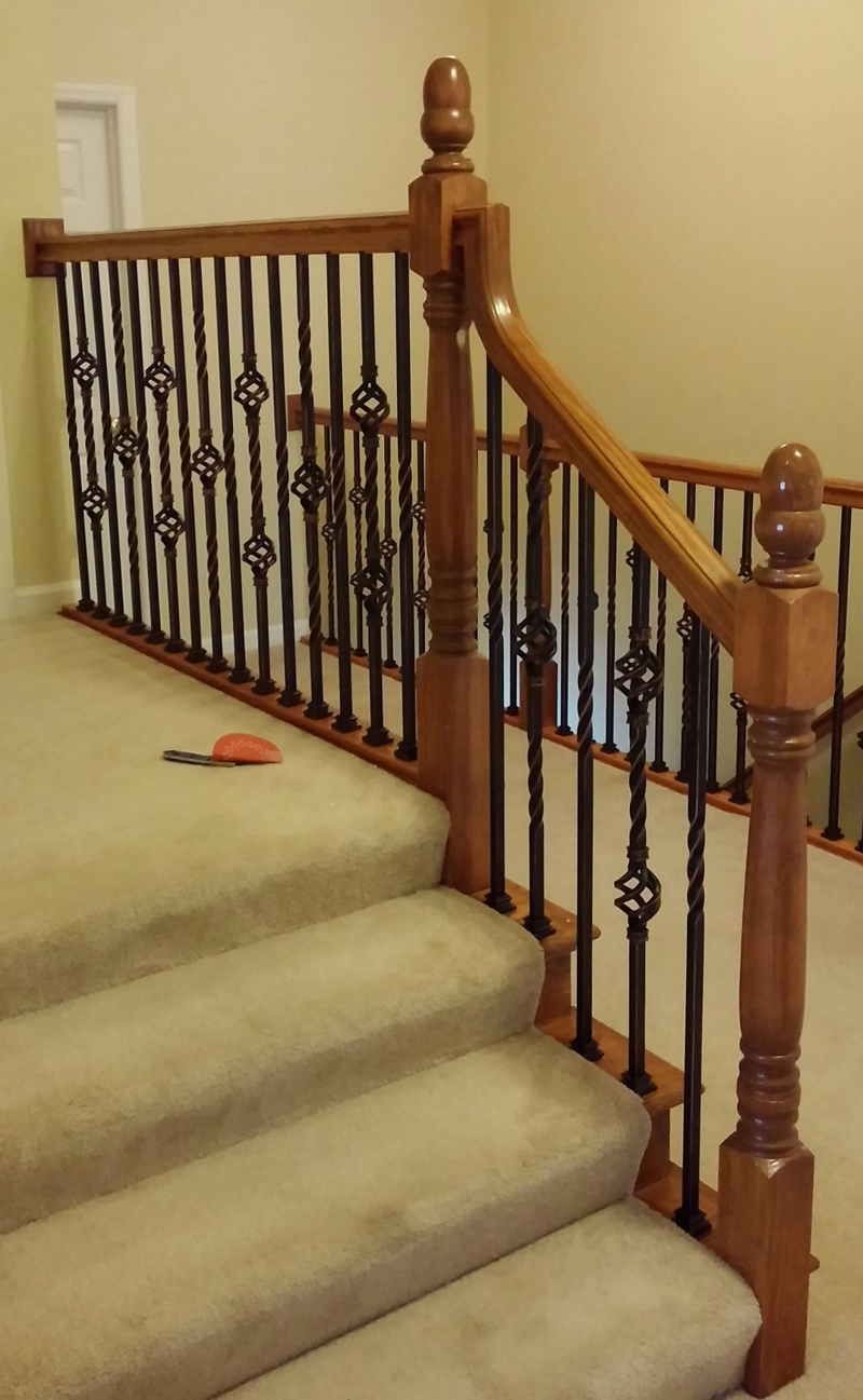 Carpeted staircase with wooden railing and black iron balusters; small toy on the stairs.