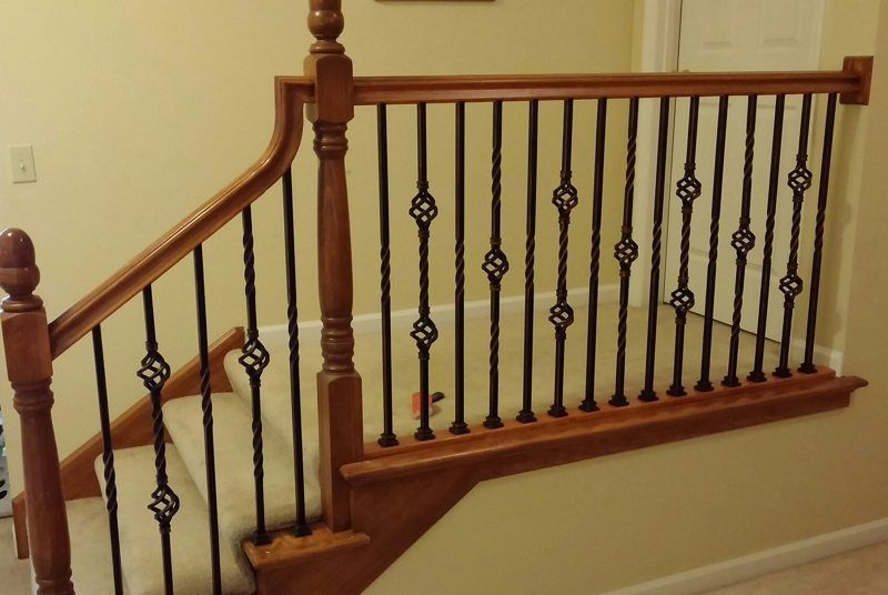 Wooden staircase with beige walls and black iron balusters in a home interior