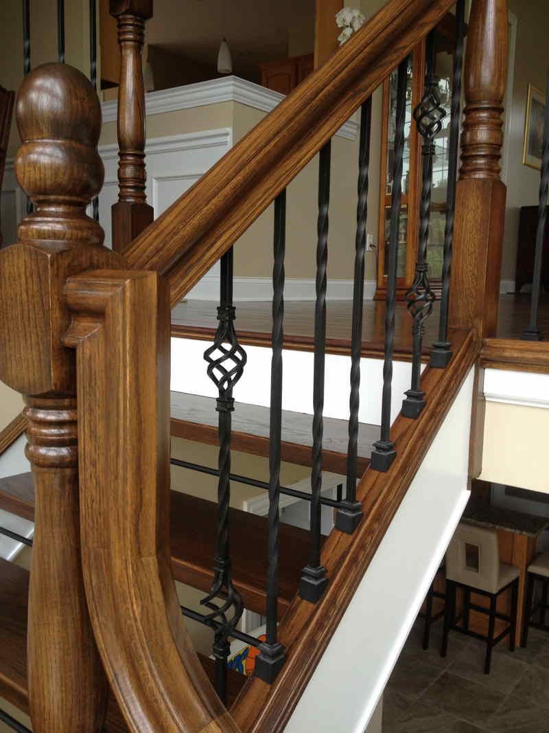 Wooden staircase with white carpet runner and black iron balusters in a home interior