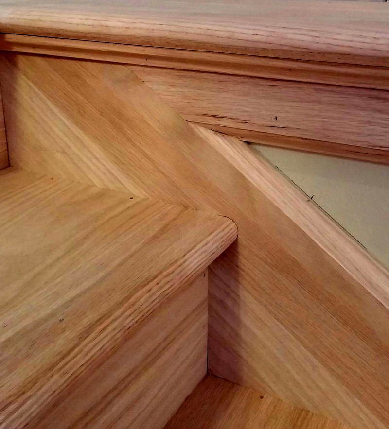 Wooden staircase with a decorative angled handrail joint and wood grain detail