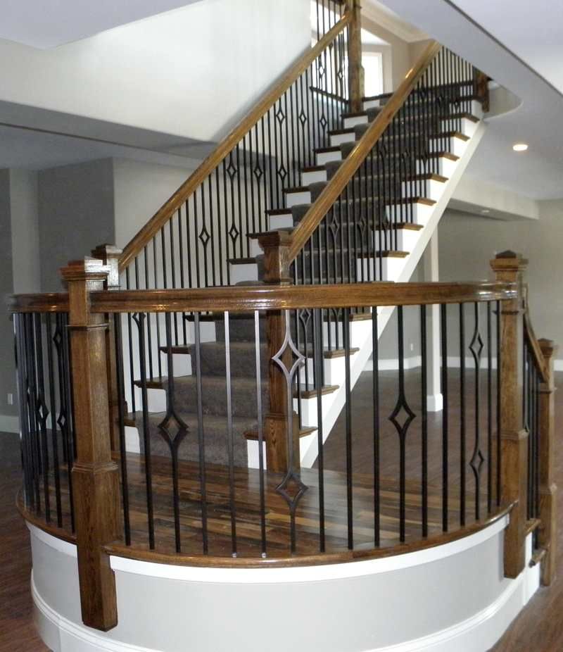Wooden staircase with black iron railing in a bright interior foyer