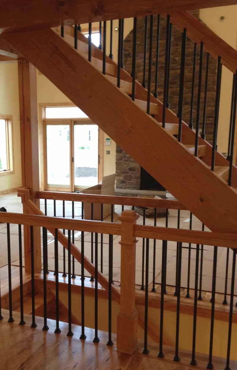 Indoor staircase with wooden banister and metal balusters in a sunlit hallway