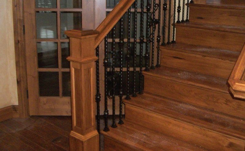 Wooden staircase with turned banister posts beside a glass-paneled door.