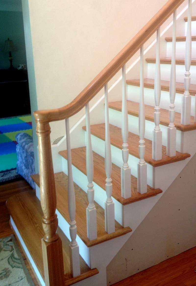Indoor wooden staircase with white balusters and a curved handrail along a beige wall.