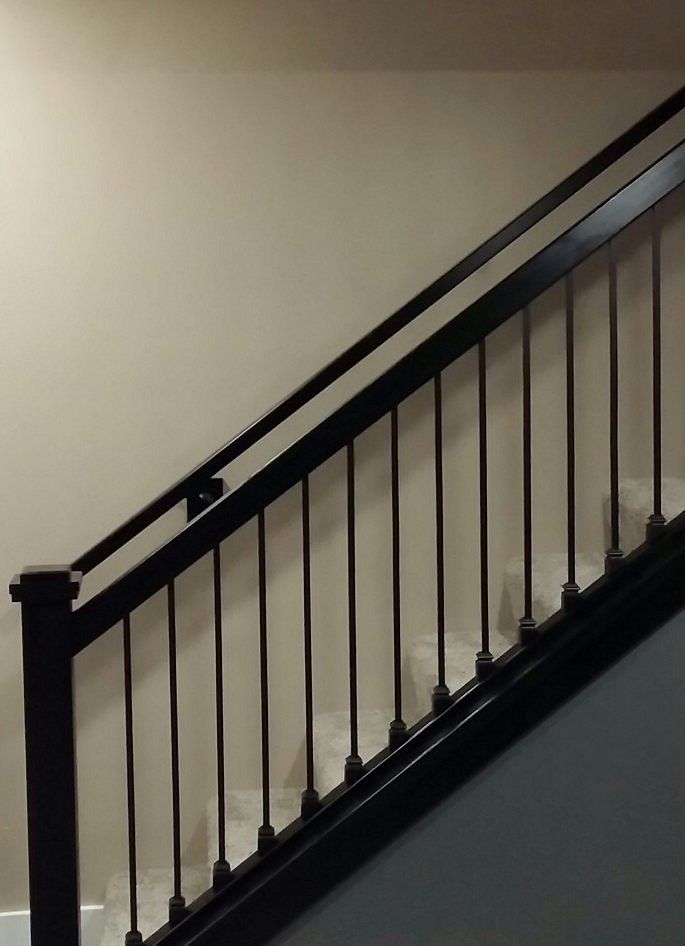 Black staircase railing on beige and gray interior wall.