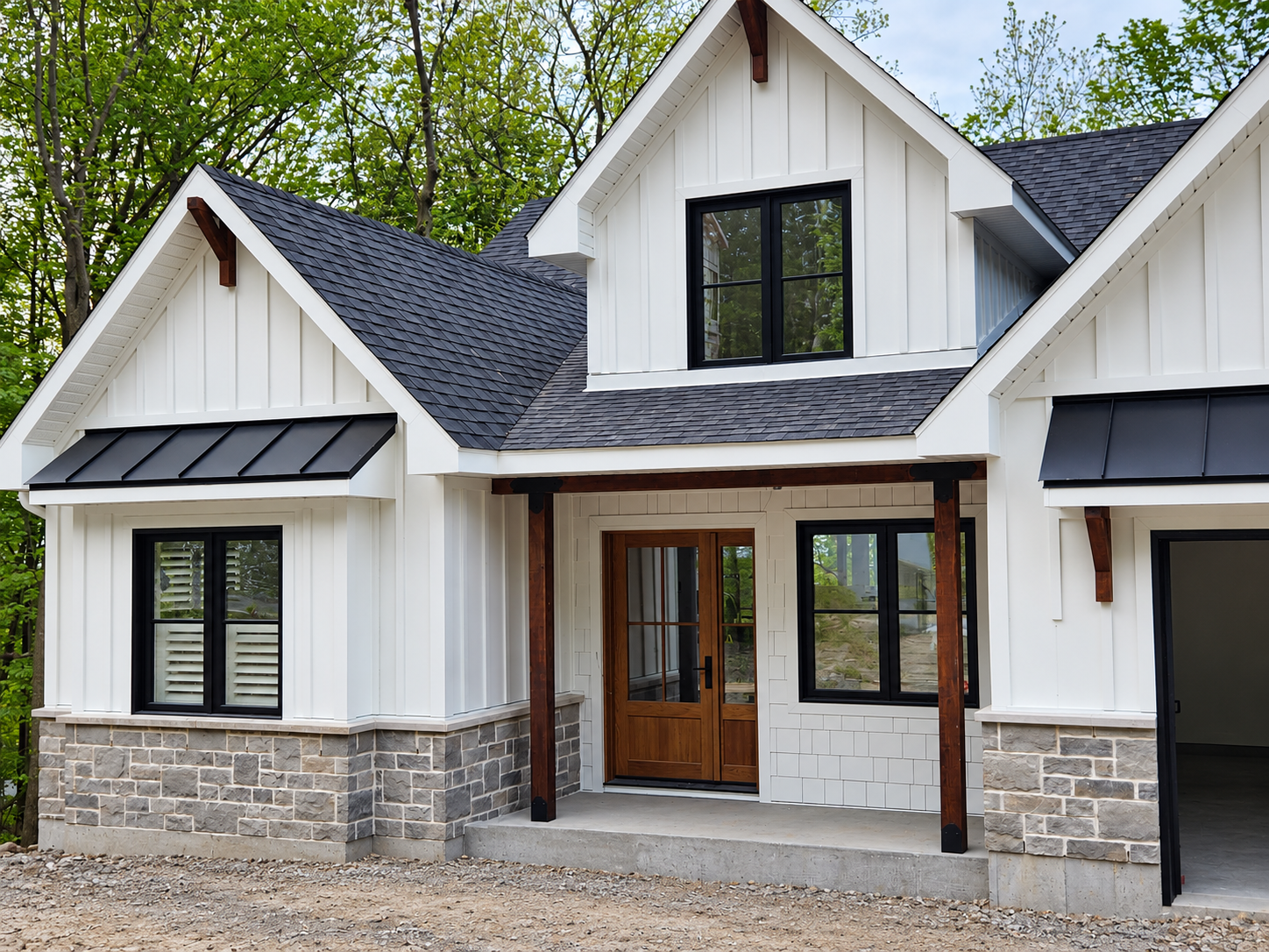 Extérieur d’une maison moderne blanche avec des touches de pierre, un toit noir et un porche d’entrée couvert