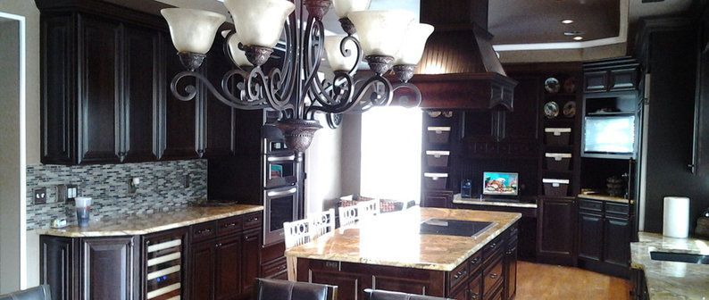 Modern kitchen with dark wood cabinets, granite island, and pendant lights