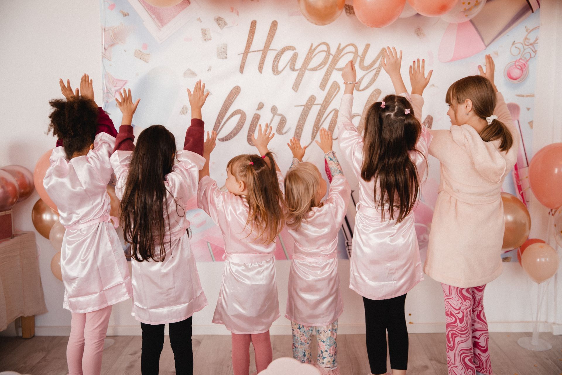 Eine Gruppe junger Mädchen steht vor einem „Happy Birthday“-Schild.