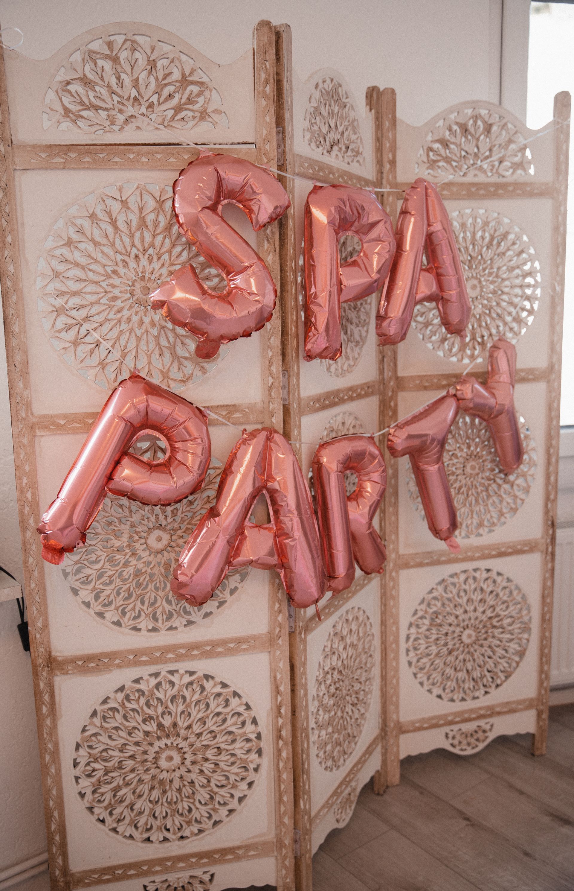 Ein Raumteiler mit rosa Luftballons, die das Wort „Spa-Party“ bilden.
