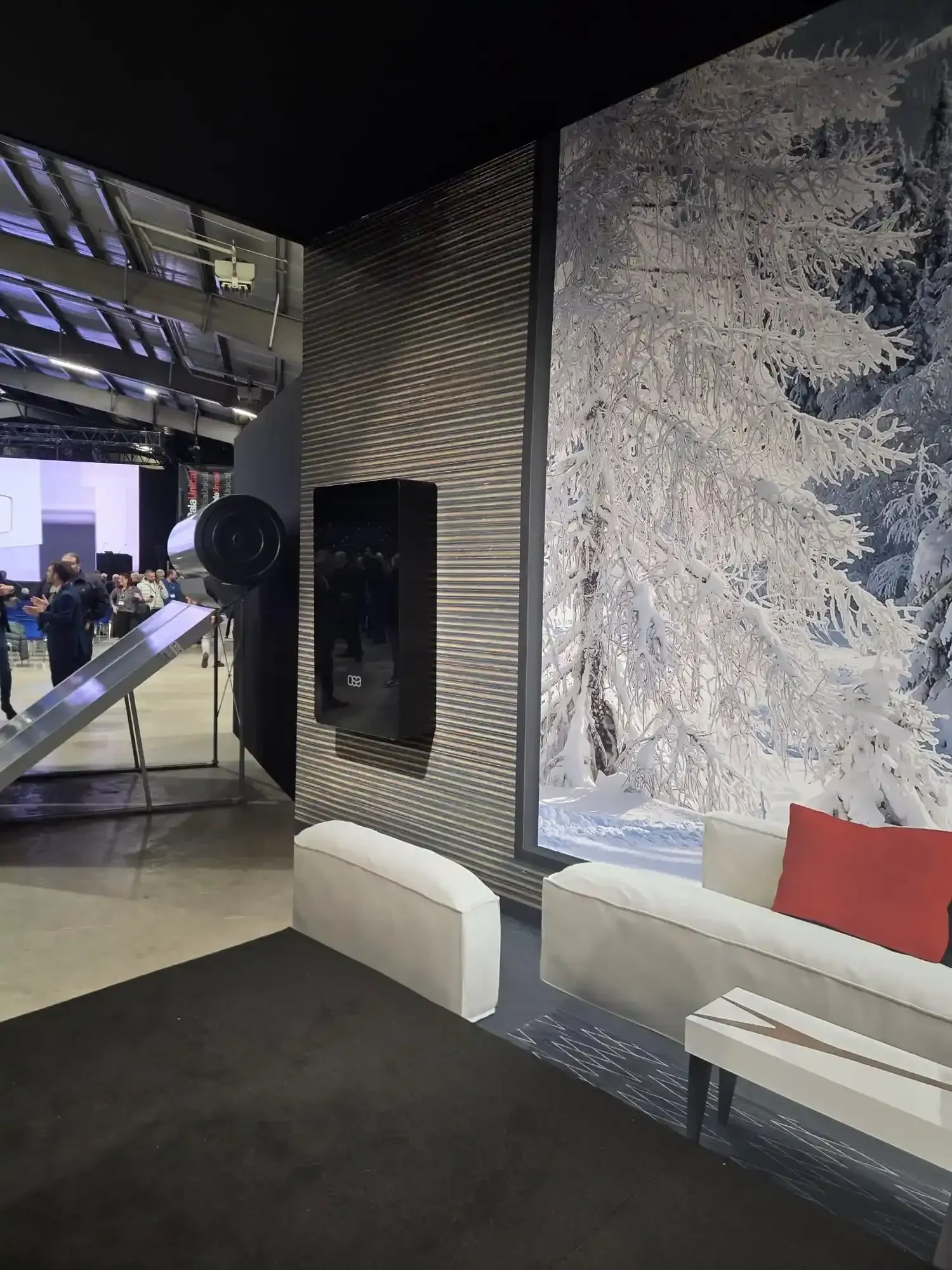 Hall moderna con pavimento nero, sedute bianche, cuscini rossi e un grande quadro murale raffigurante un paesaggio invernale.