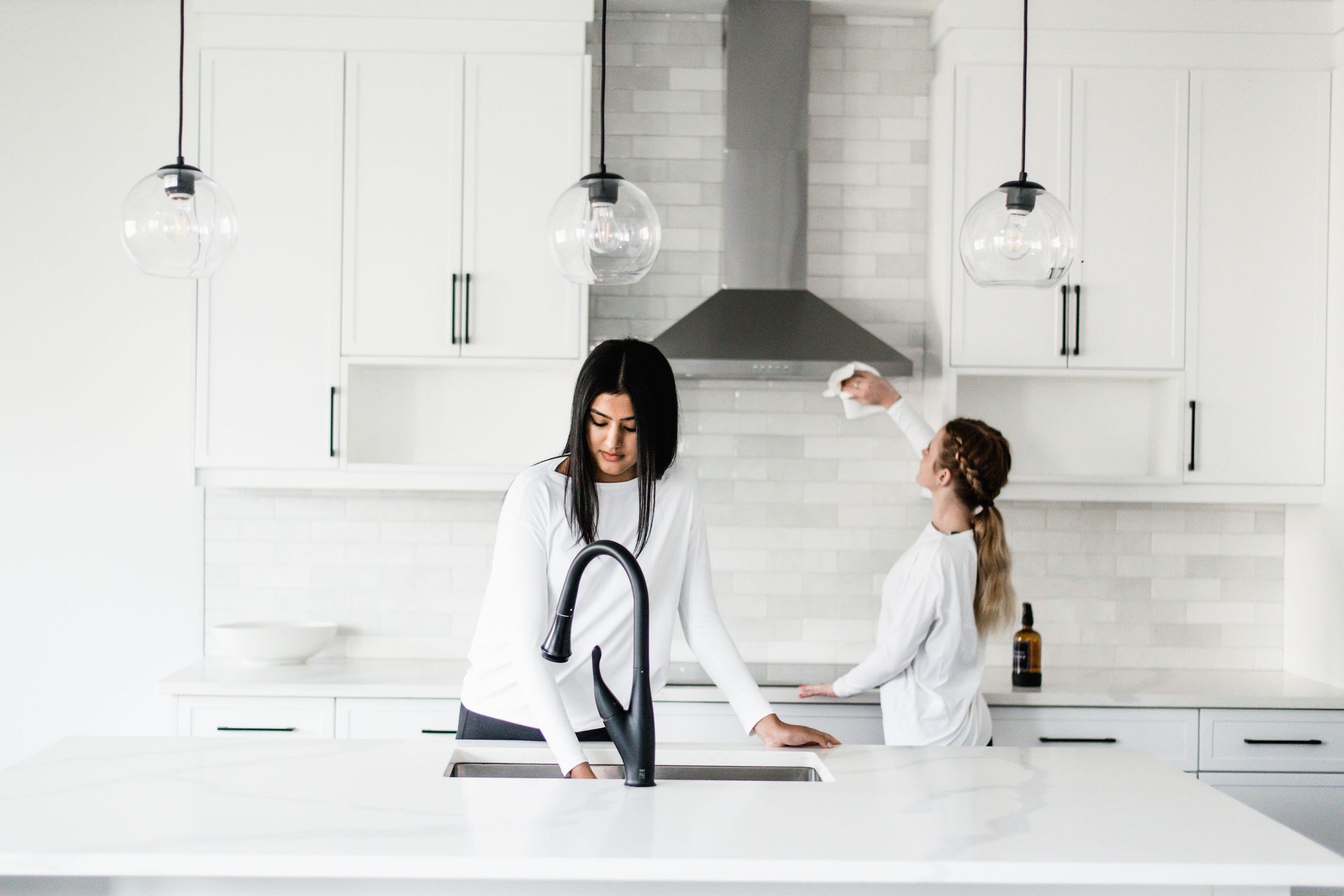 Two women in a white kitchen.