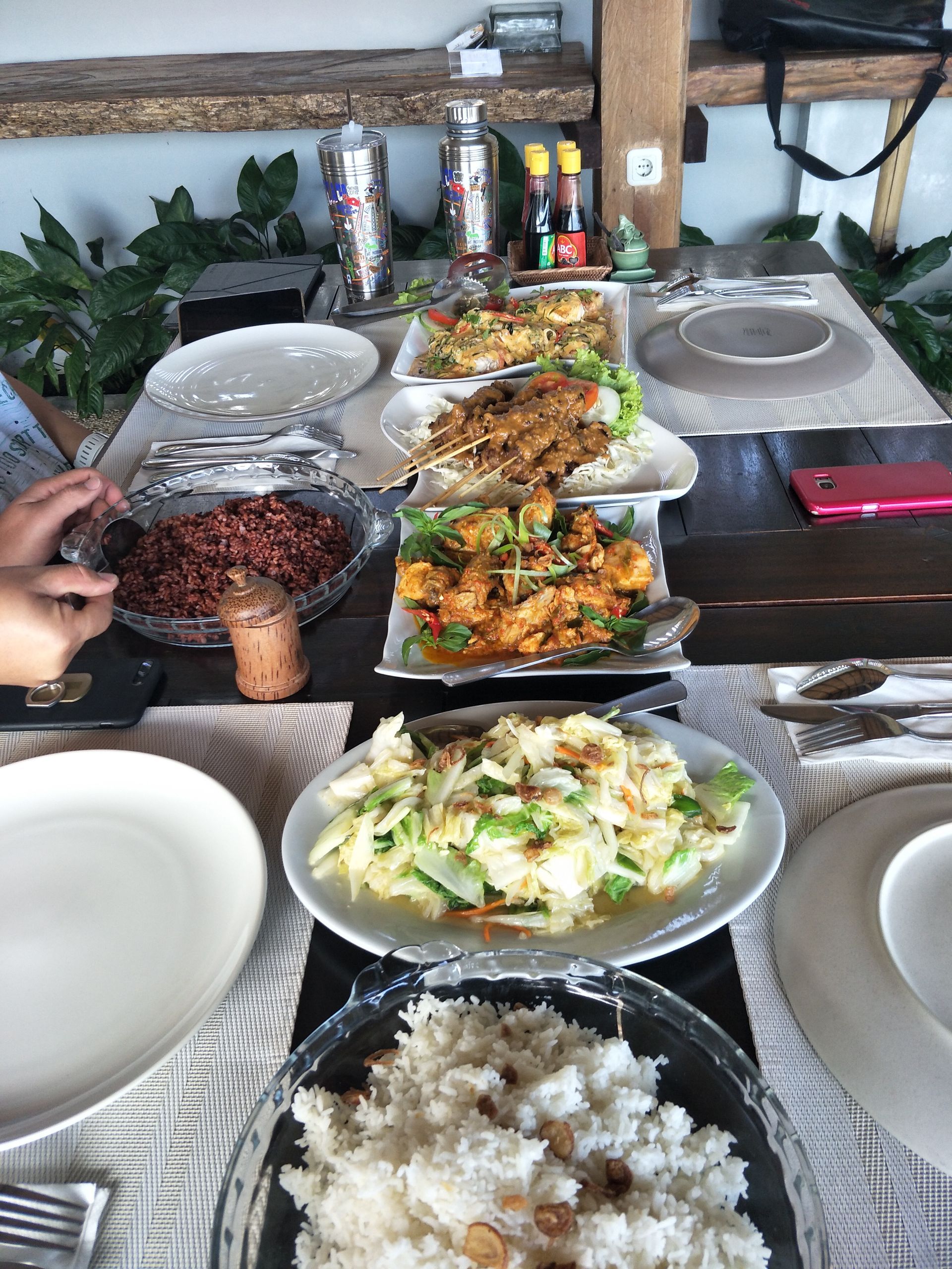 Lembeh food - Table set with several platters of food, plates, and condiments on a dining table