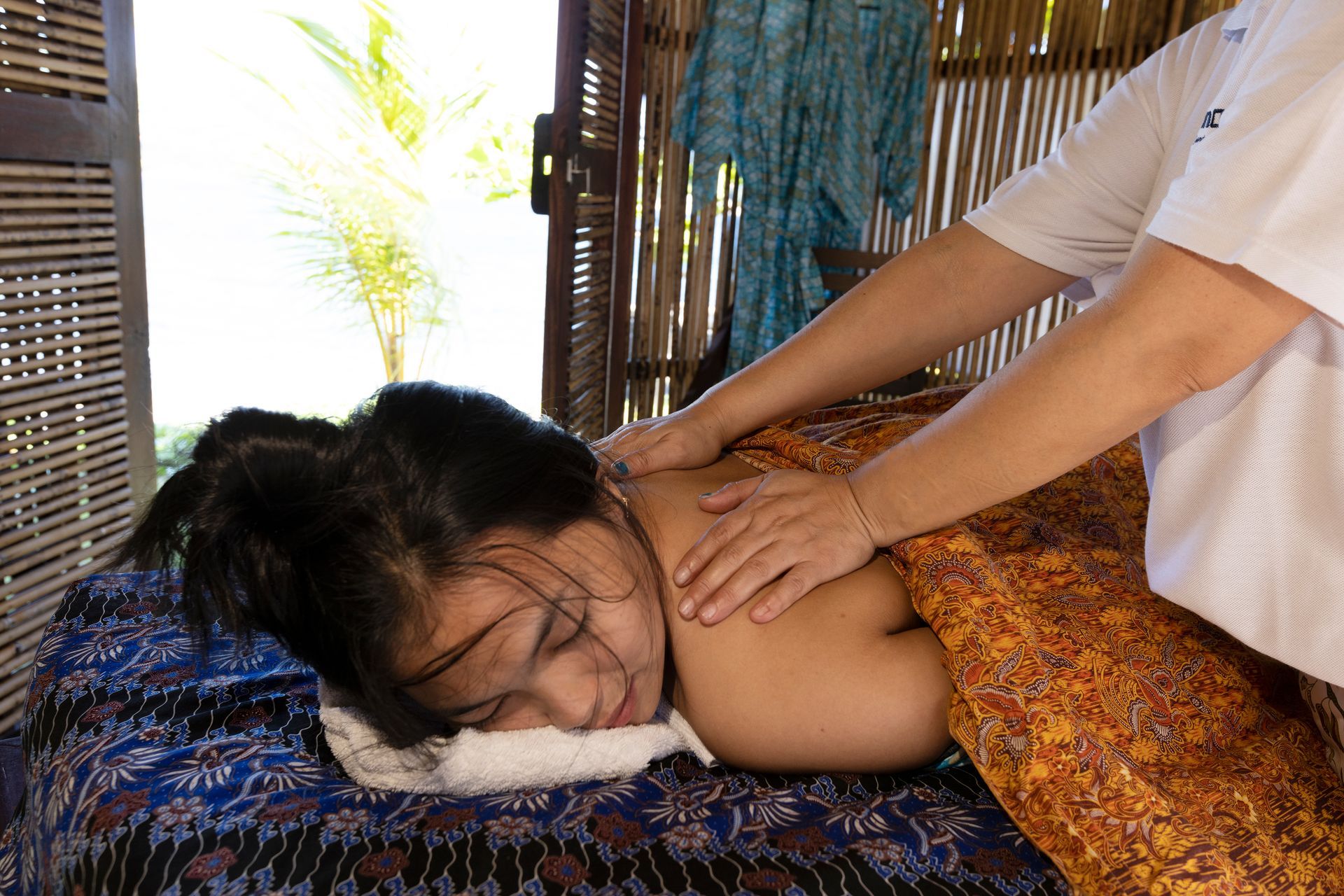 Person receiving a back massage on a cushioned mat in a spa setting