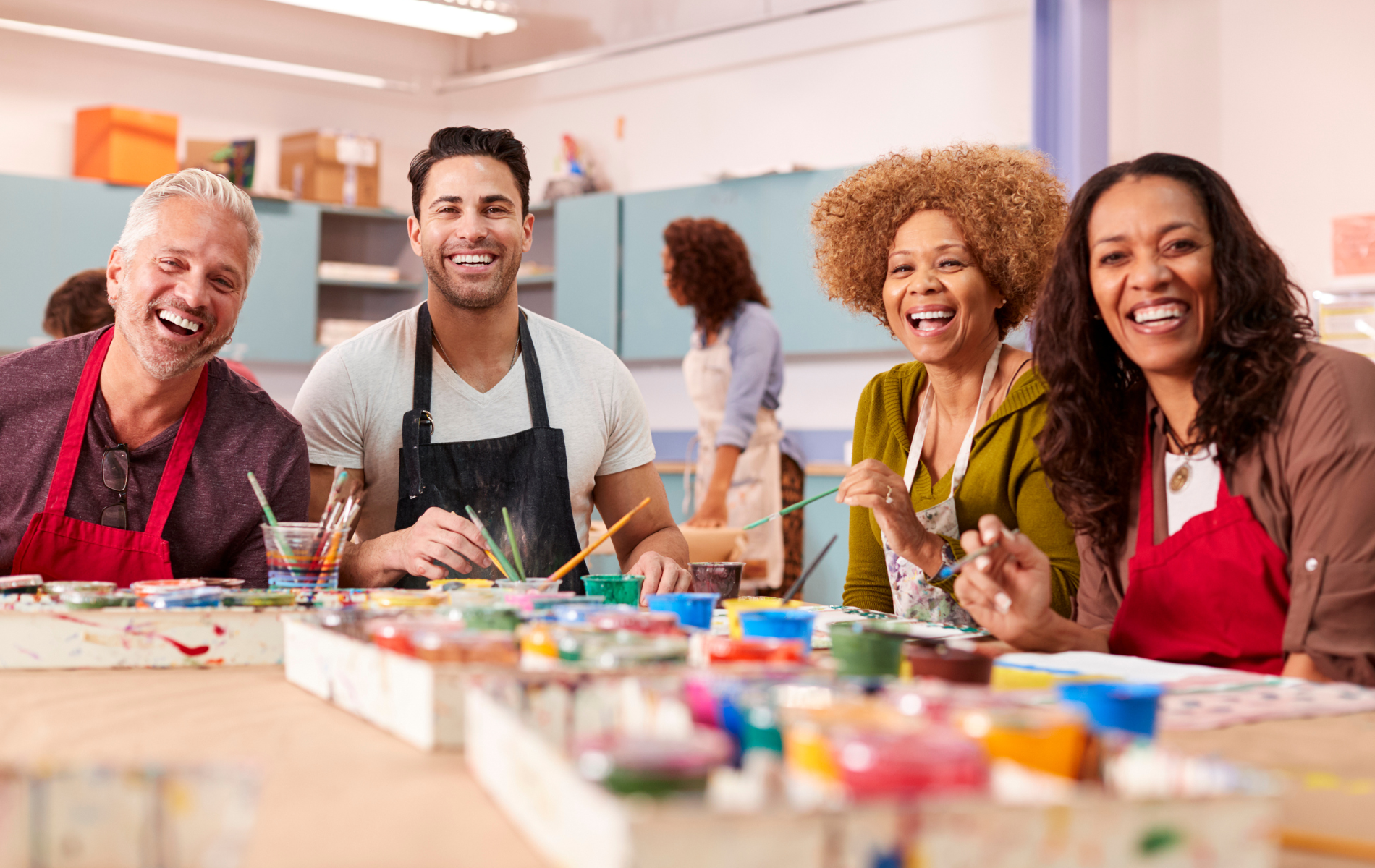 A group of people are sitting at a table painting.