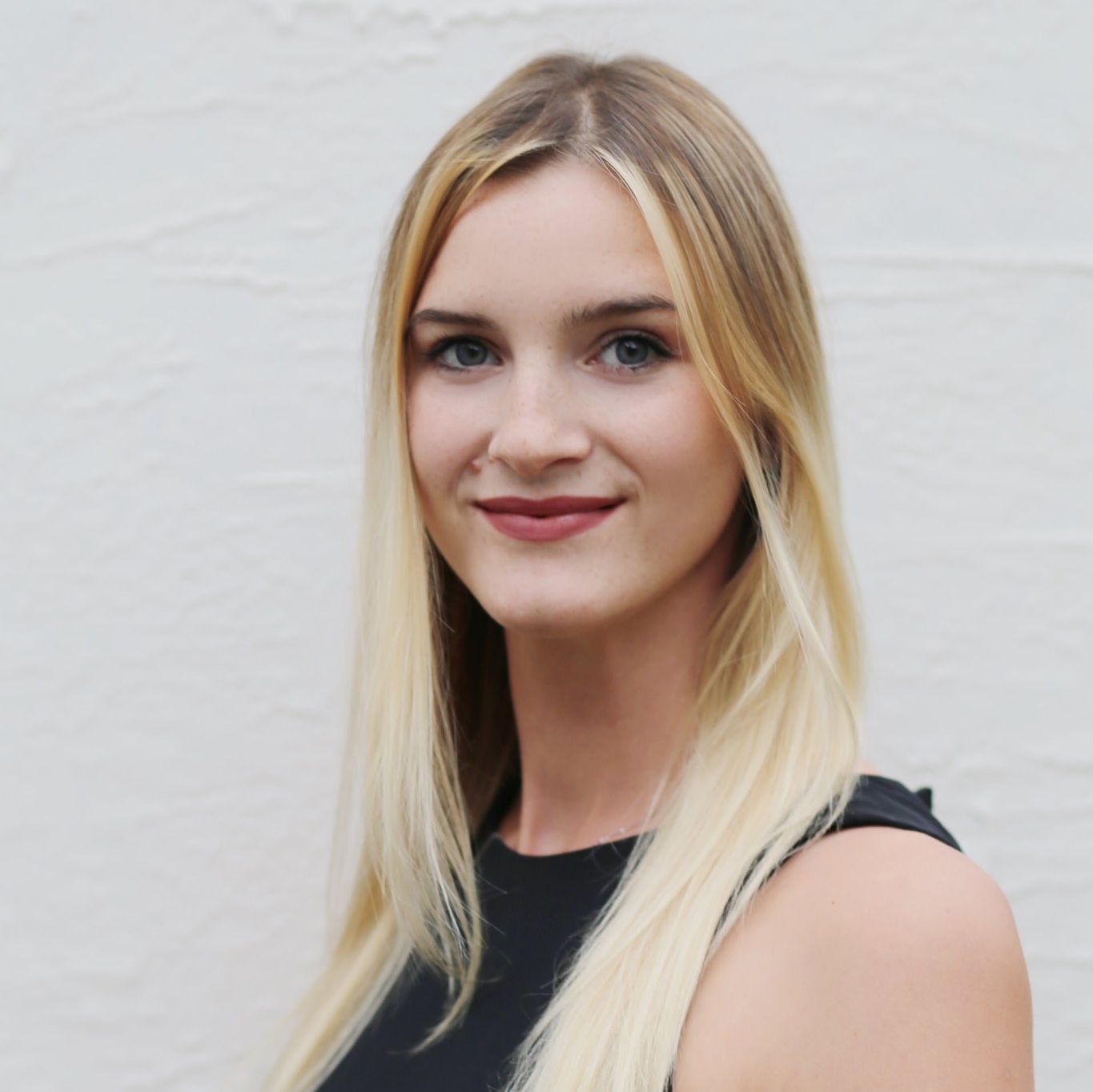A woman with long blonde hair is wearing a black top