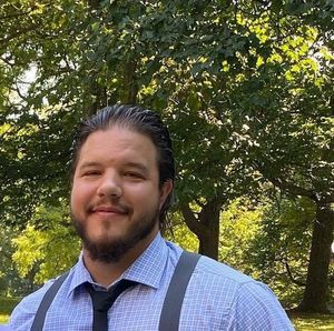 A man with a beard is wearing suspenders and a tie.