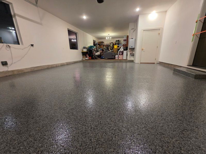 Garage with shiny gray speckled epoxy floor and white walls.