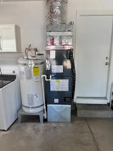 Home utility area with water heater, furnace, and washer near a door and utility sink.