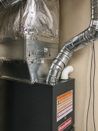 HVAC furnace with silver ductwork and insulated venting in a utility closet