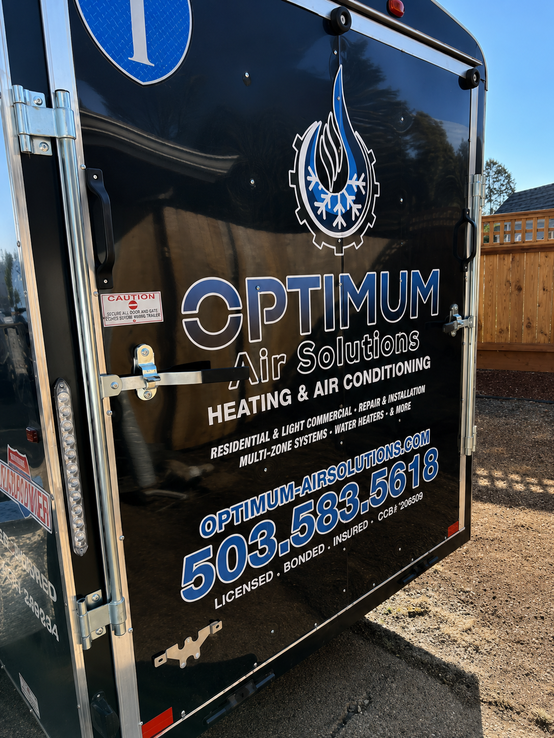 Black HVAC service trailer with Optimum Air Solutions logo and contact information in silver and blue.