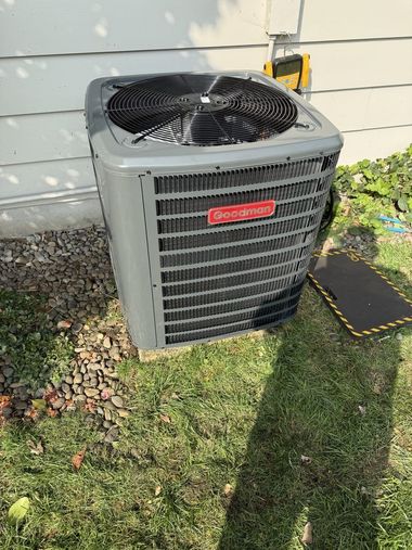Outdoor central air conditioner unit beside a house with its top fan cover damaged or removed.