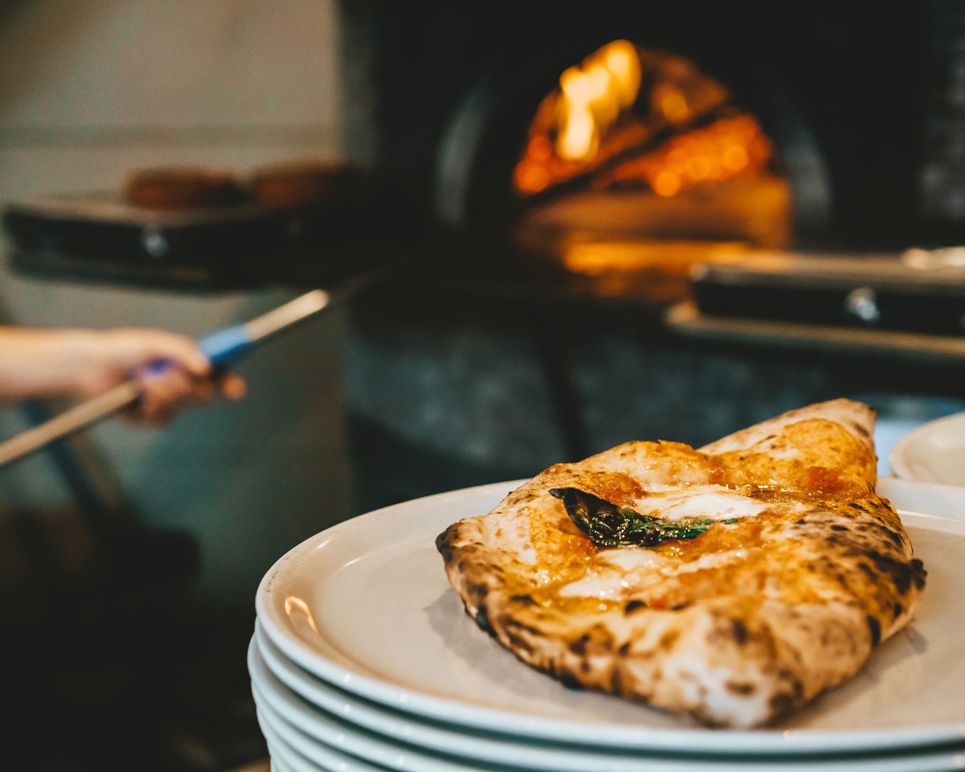Una pizza su un piatto davanti a un forno per pizza