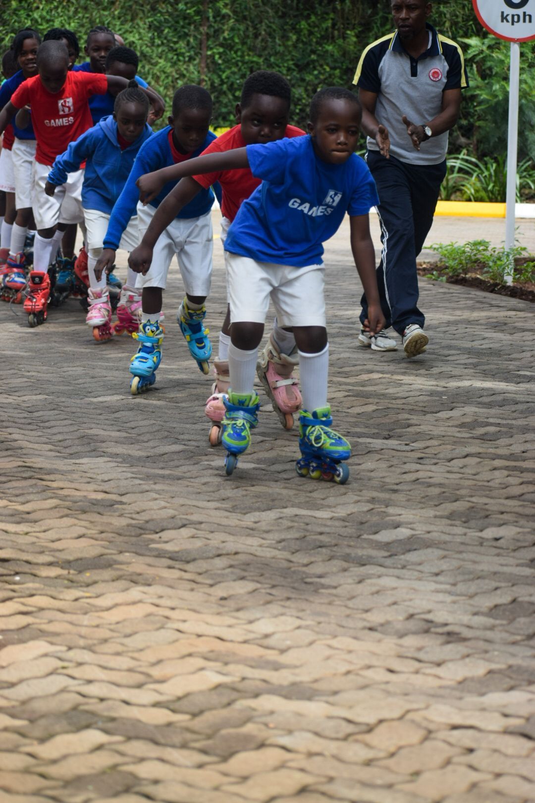 A group of children are rollerblading down a brick road.