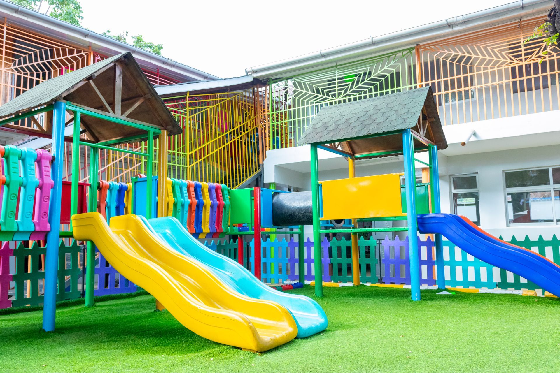 A colorful playground with a slide and a tunnel in a schoolyard.