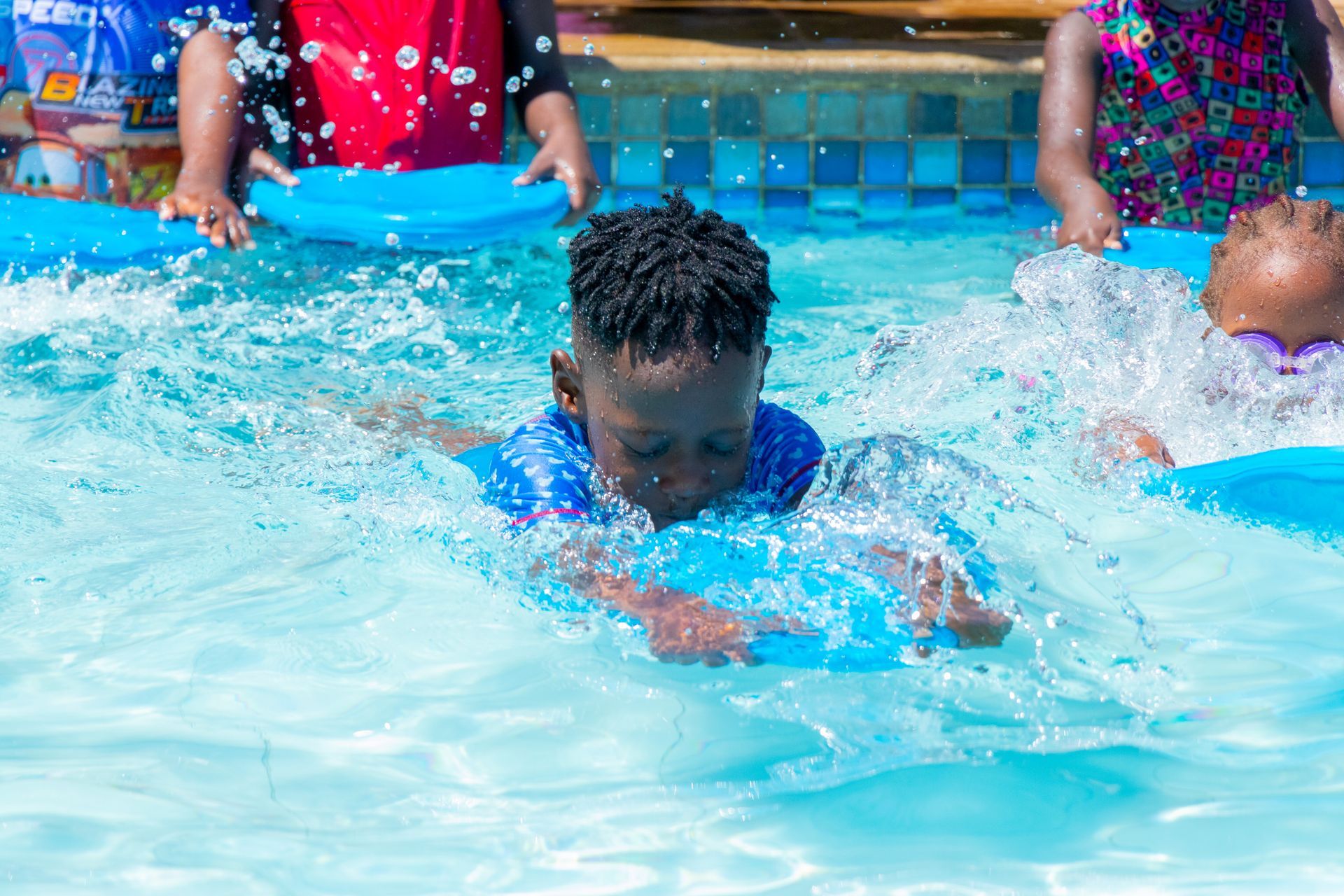 A group of children are swimming in a swimming pool.