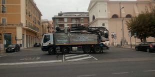 Un grosso camion sta svoltando in un incrocio cittadino con degli edifici.