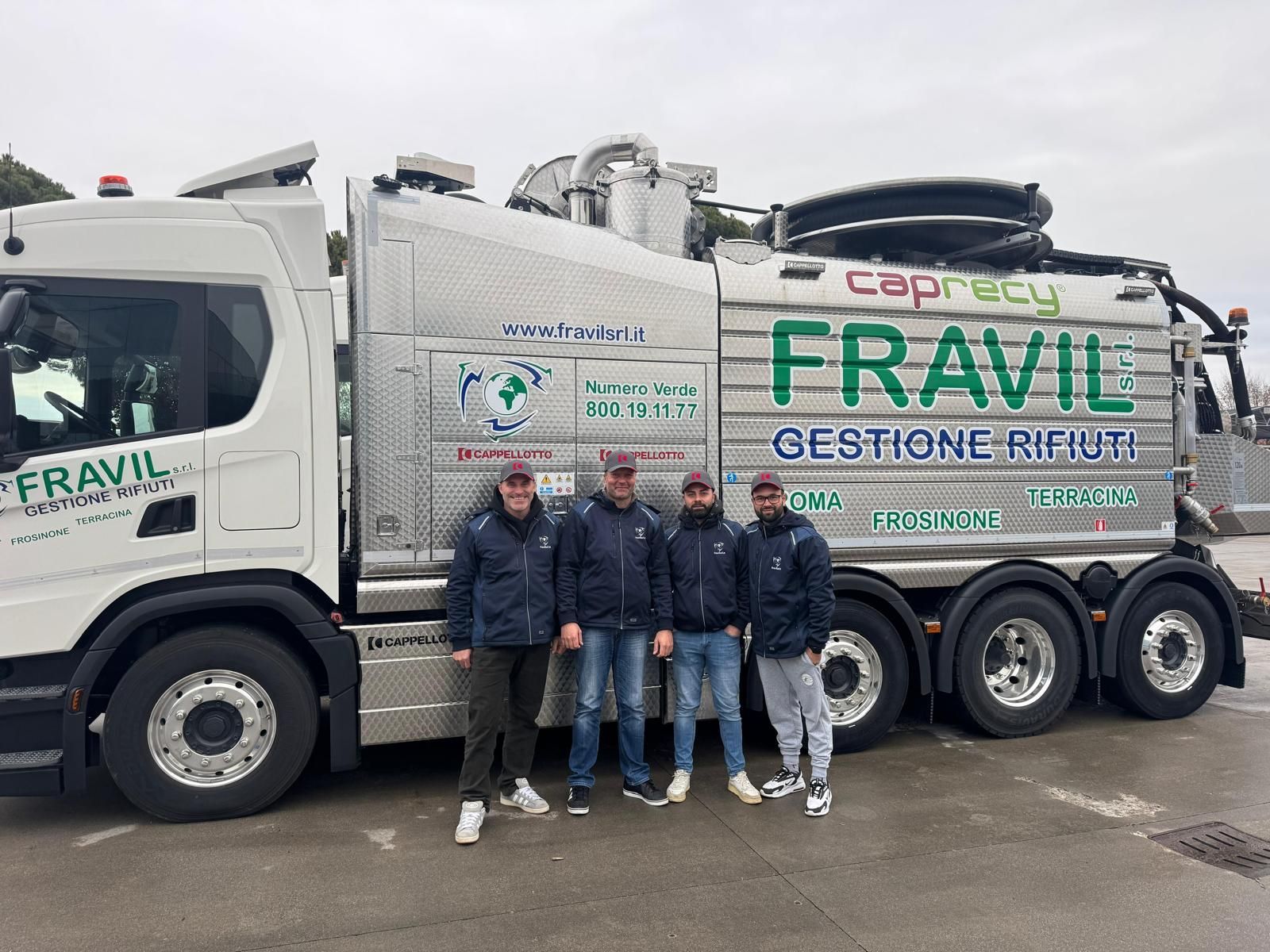 Quattro uomini posano davanti a un camion bianco con la scritta 
