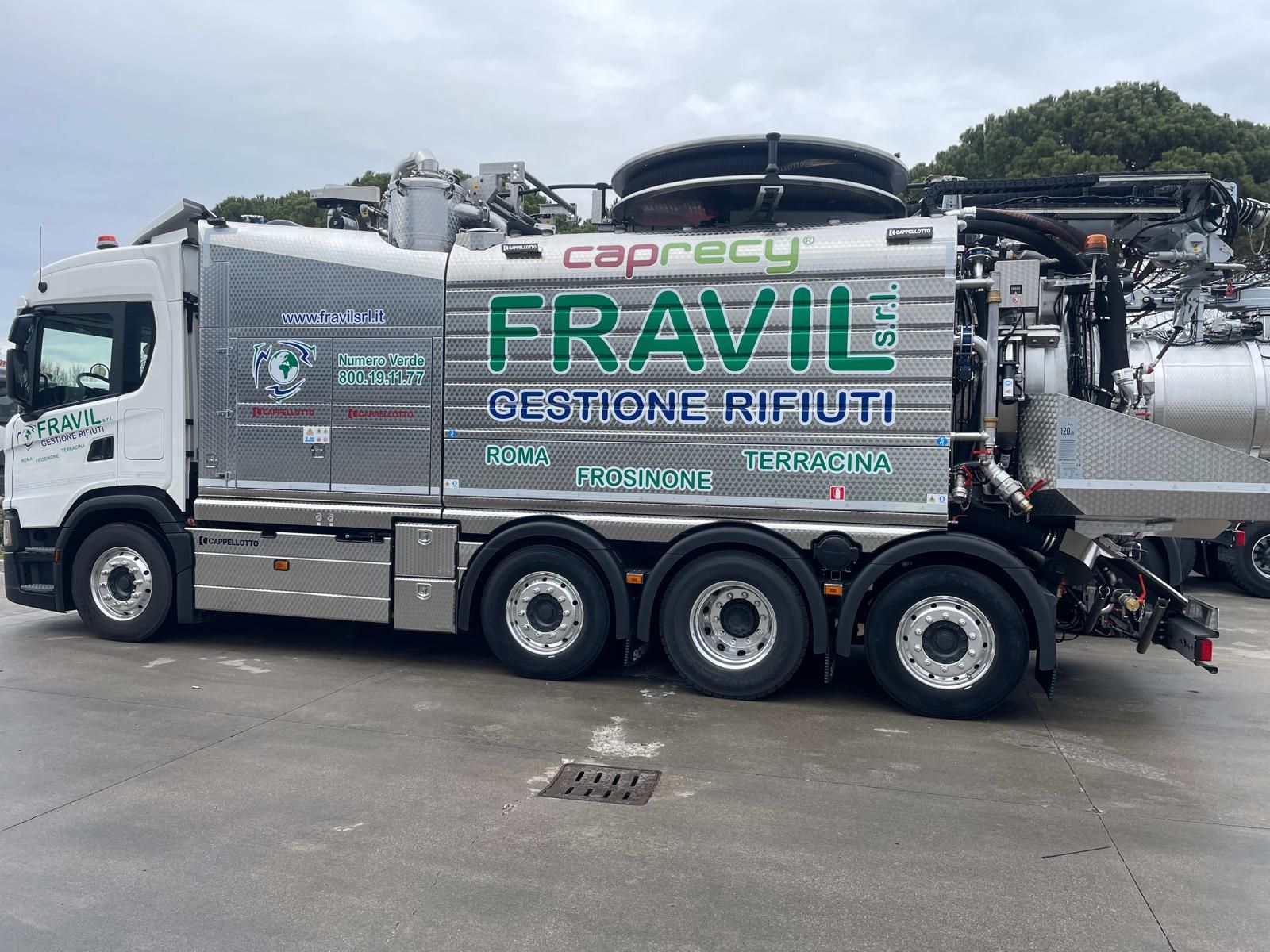Camion della spazzatura Frail bianco e grigio, con più ruote, all'aperto.