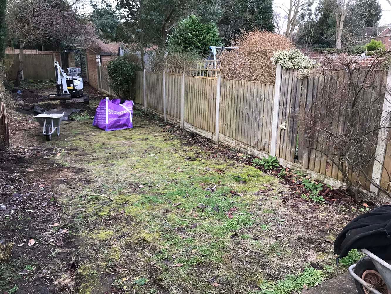 Messy backyard with muddy grass, wooden fence, and scattered garden items