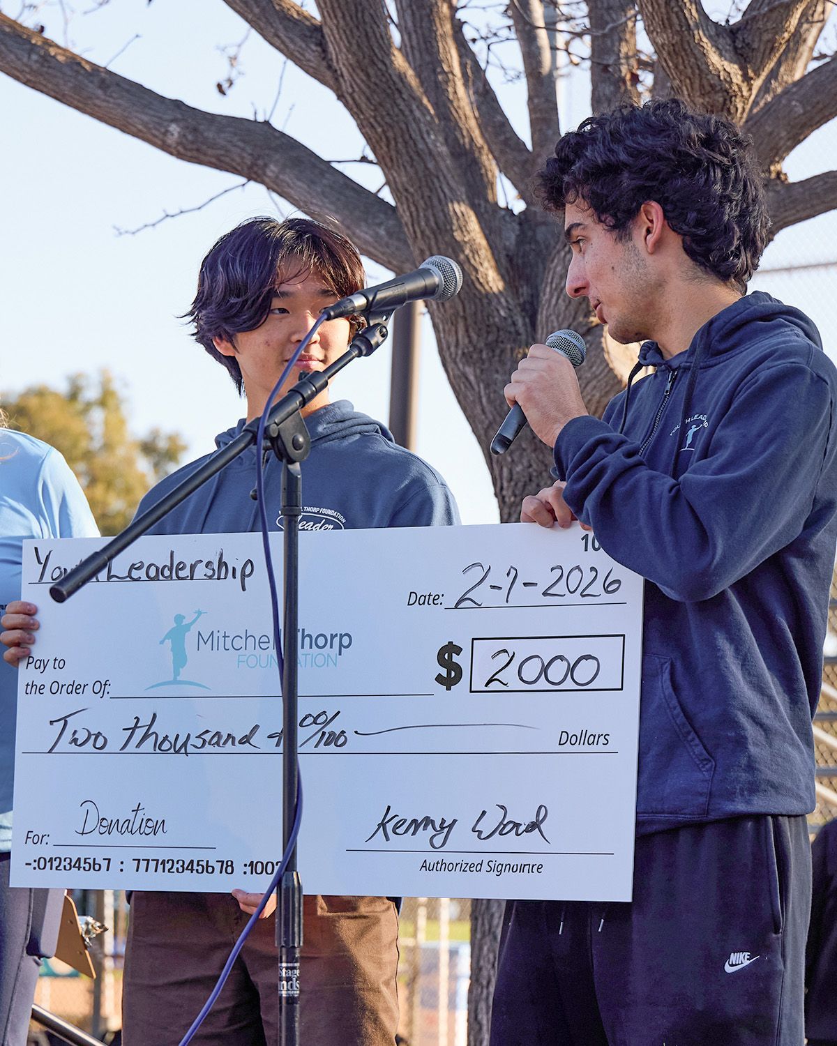 Two people hold a giant $2,000 check for a