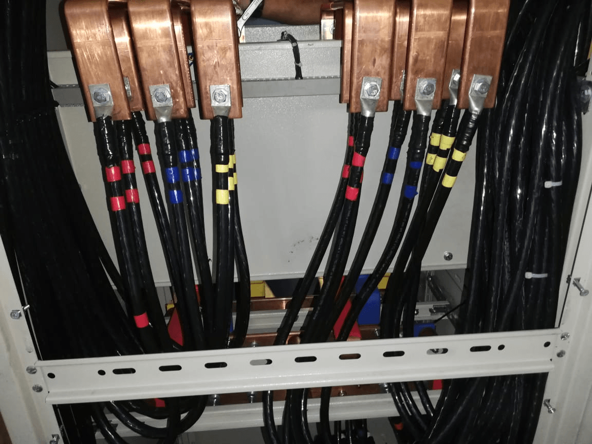 Panel eléctrico con cables negros conectados a barras colectoras de cobre