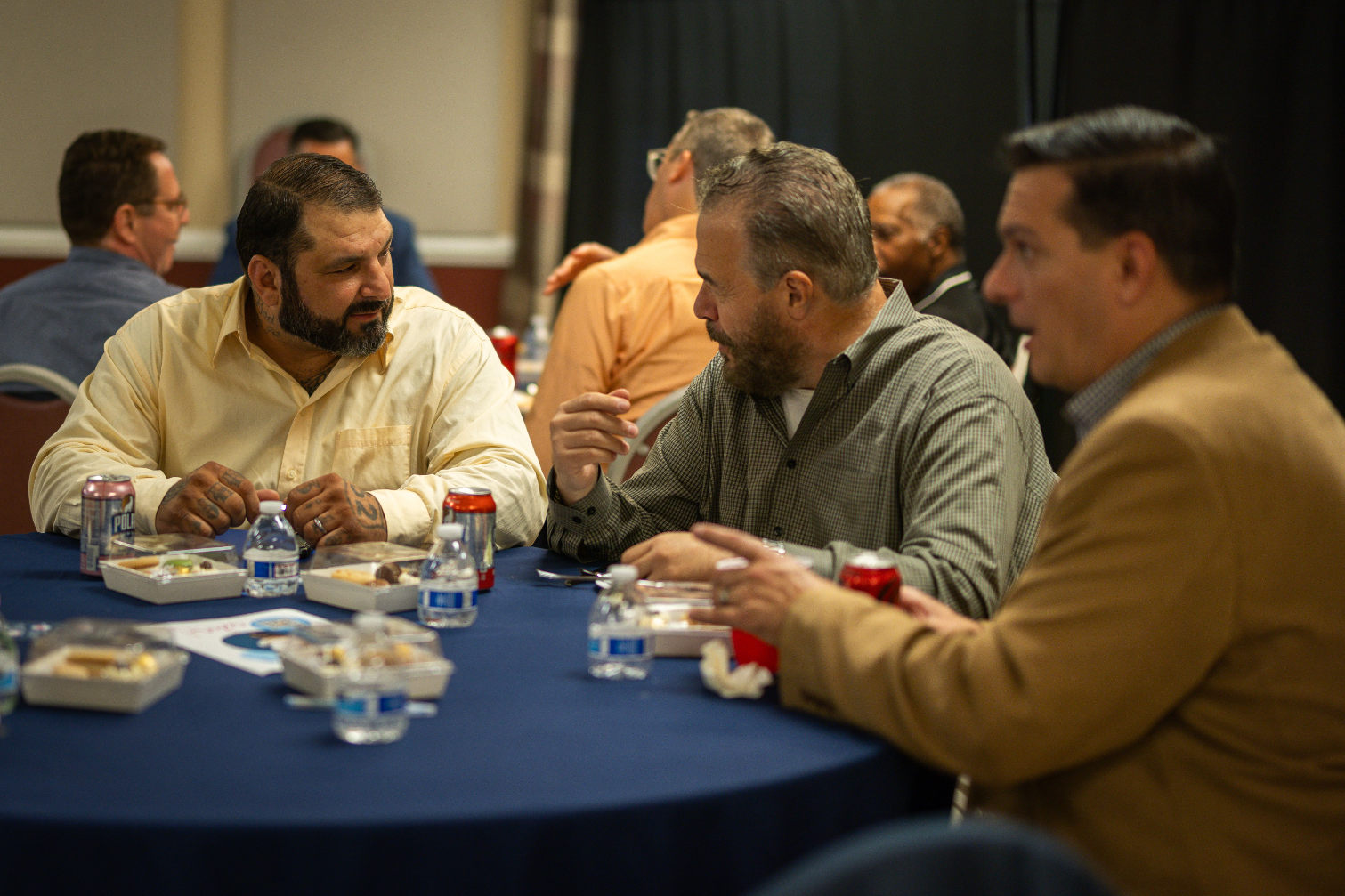 A group of men are sitting at a table eating and drinking.
