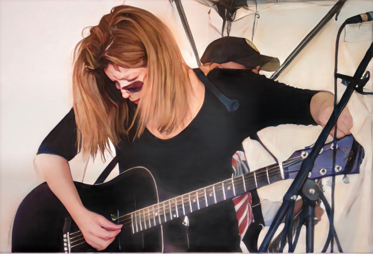 A woman is playing a guitar in front of a microphone