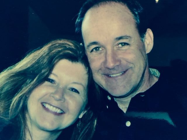 A man and a woman are posing for a picture and smiling for the camera