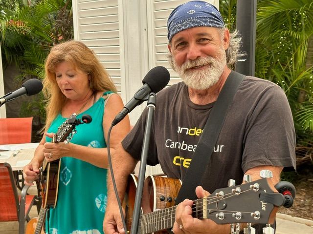 A man and a woman are playing guitars and singing into microphones
