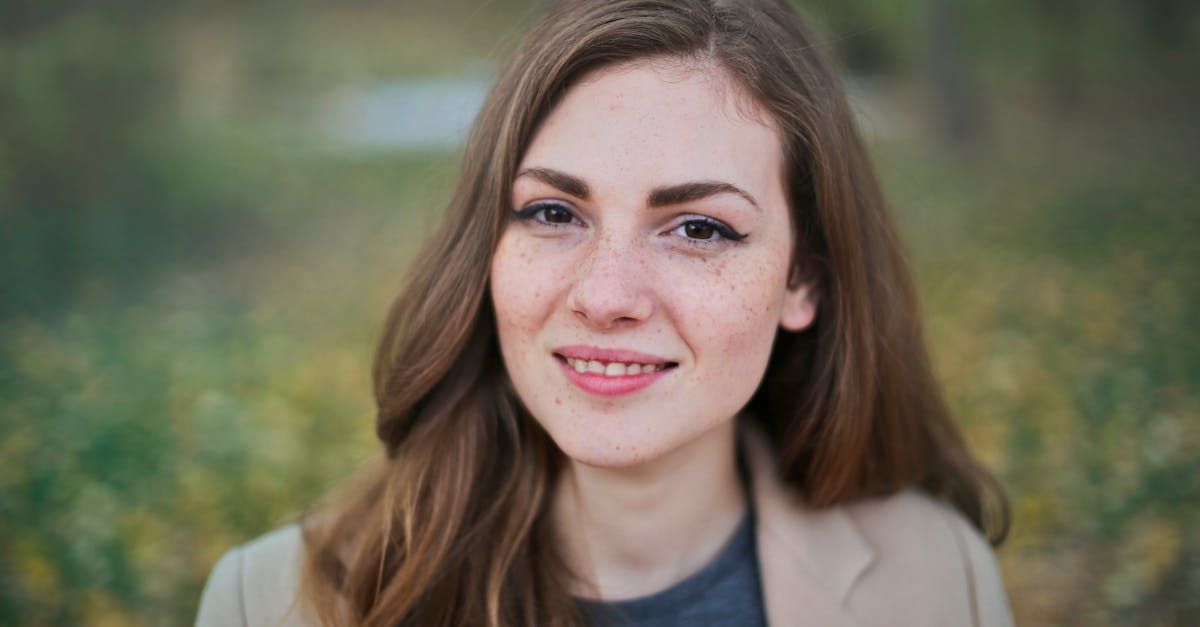 A close up of a woman 's face with a field of flowers in the background.